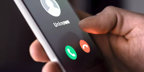 Hand holding a cell phone displaying an unknown caller.